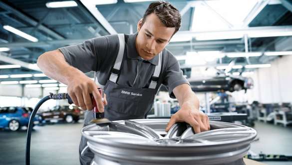 A BMW Service employee reparing the rim of a BMW. A BMW Service employee reparing the rim of a BMW.