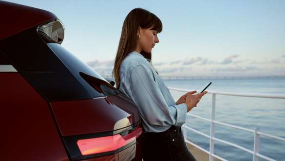 My BMW App BMW Repair and Care BMW Repair and Care My BMW App woman with smartphone in hands leaning against BMW vehicle