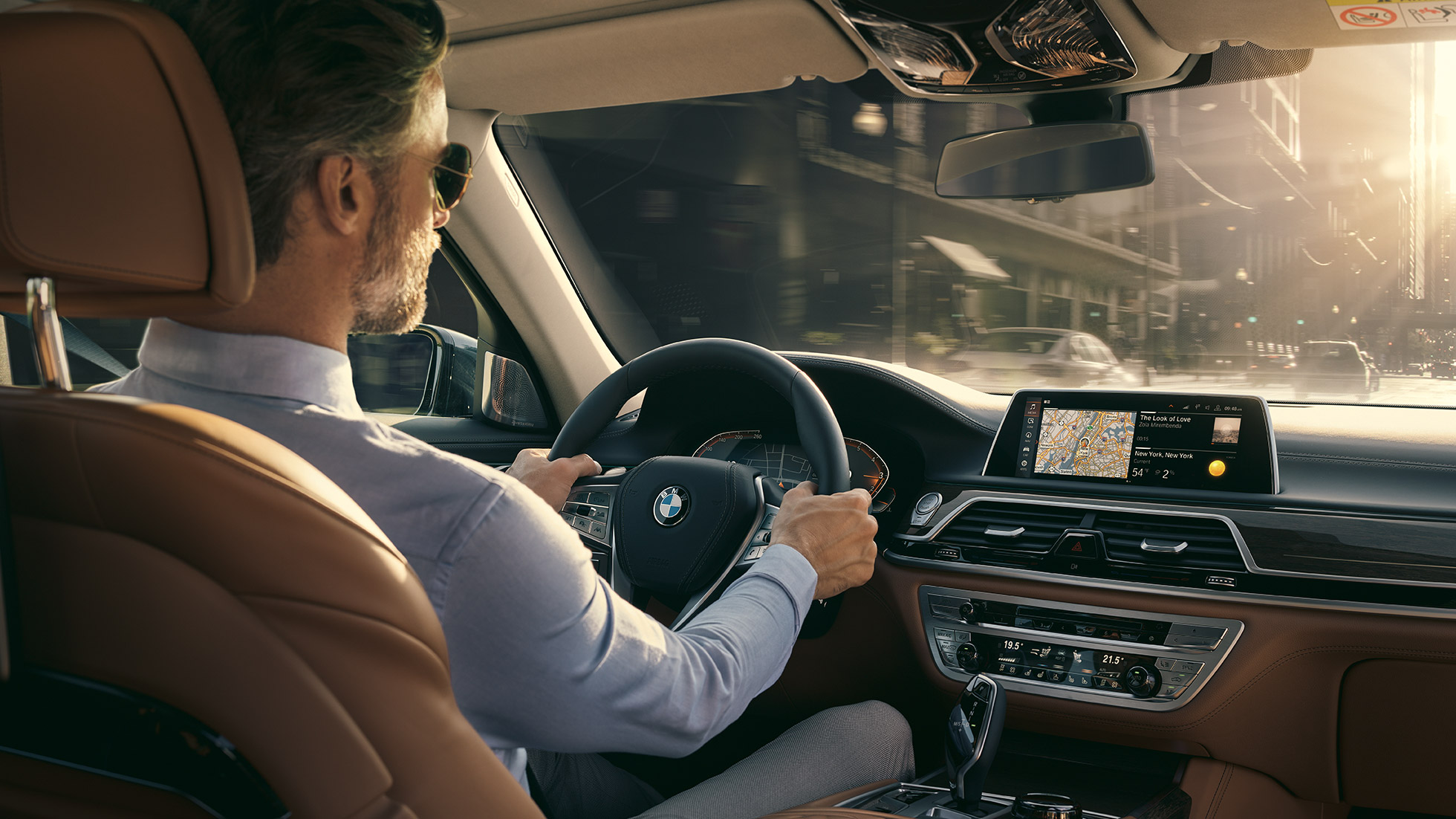 BMW 7 Series Sedan G11 Connectivity features BMW 7 Series Sedan G11: man sits in BMW and uses Connectivity features