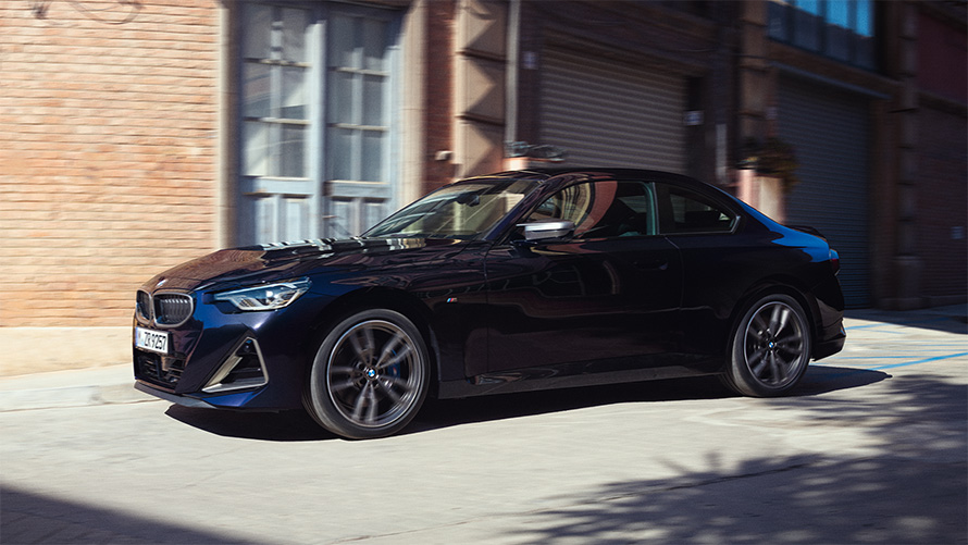 BMW M240i xDrive Coupé G42 2021 Black Sapphire metallic side view standing in front of warehouse