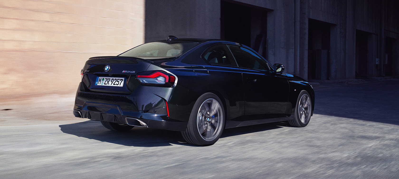 Three-quarter rear view BMW M240i xDrive Coupé G42 2021 BMW M240i xDrive Coupé G42 2021 Black Sapphire metallic three-quarter rear view driving