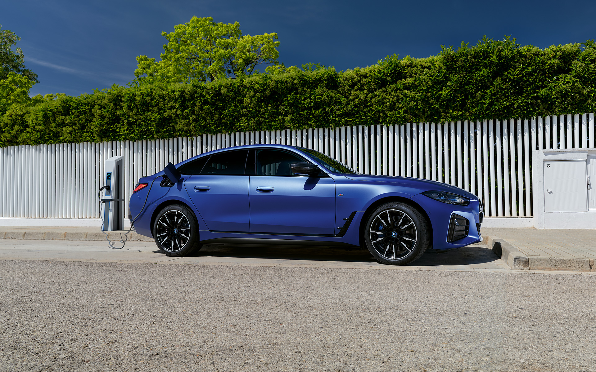 BMW i4 M50 G26 2021 BMW Individual Frozen Portimao Blue metallic side view connected to charging pole