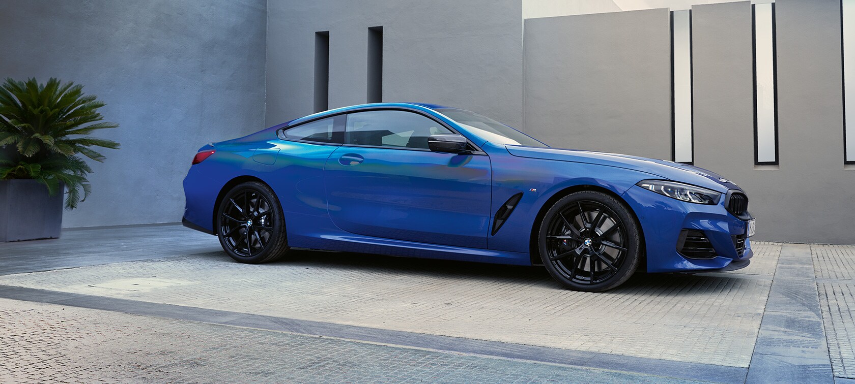 Side view BMW M850i xDrive Coupé G15 LCI Facelift 2022 BMW M850i xDrive Coupé G15 LCI Facelift 2022 M Portimao Blue metallic side view standing in front of a building