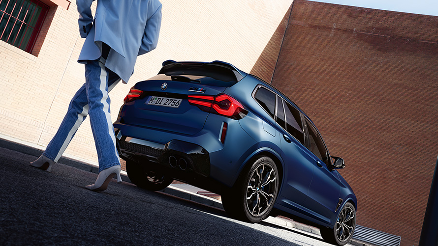 BMW X3 M Competition F97 LCI 2021 three-quarter rear view with model low angle shot BMW X3 M Competition F97 LCI Facelift 2021 Frozen Marina Bay Blue metallic three-quarter rear view with model low angle shot