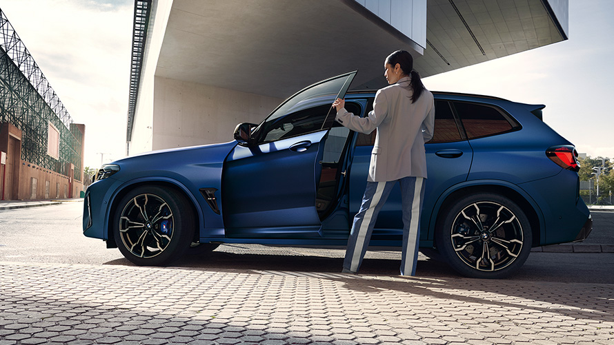 BMW X3 M Competition F97 LCI 2021 side view with open door and female model BMW X3 M Competition F97 LCI Facelift 2021 Frozen Marina Bay Blue metallic side view with open door and female model