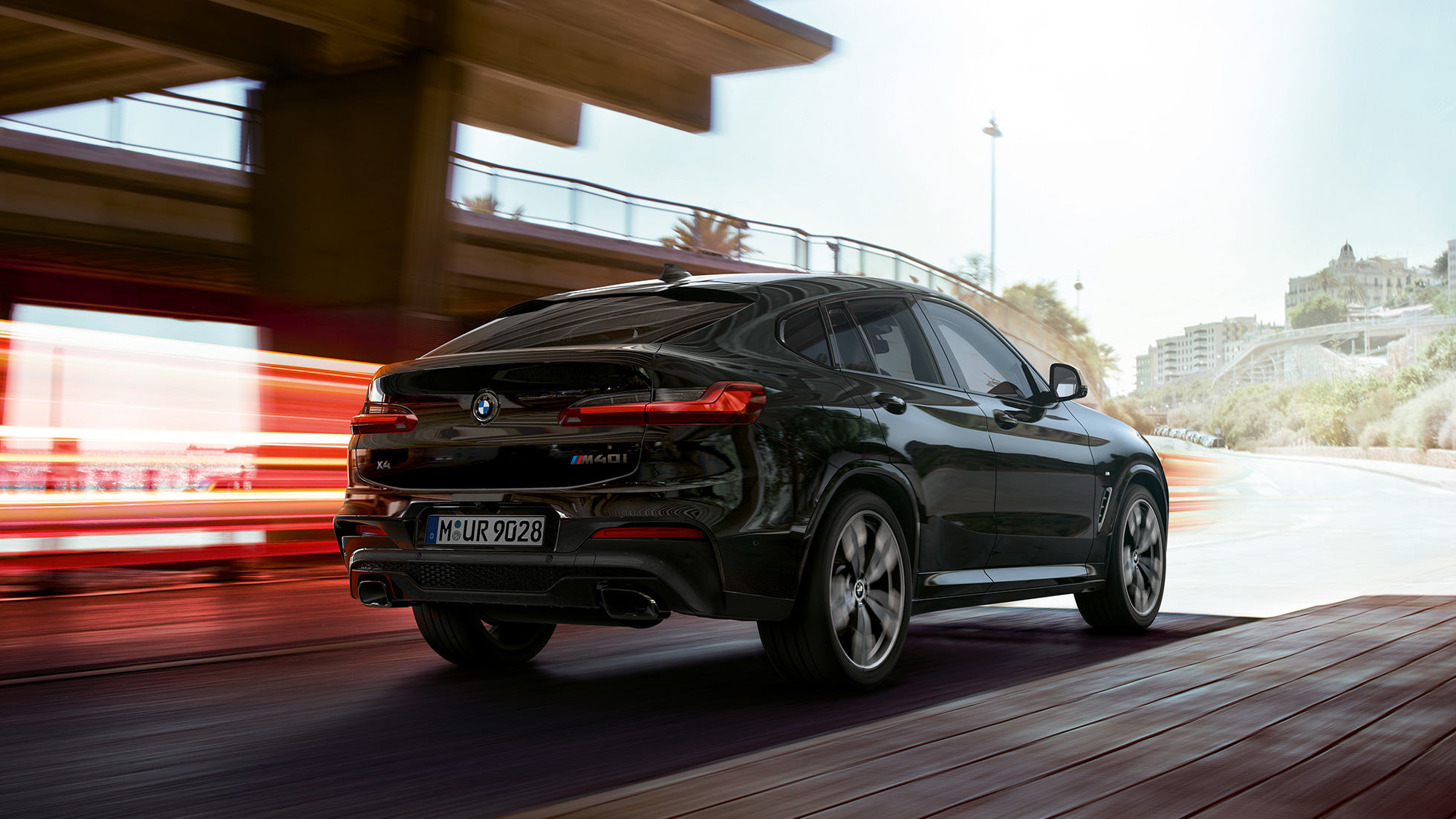 BMW X4 M40i SUV in, three-quarter front view F98. BMW X4 M40i SUV in Black Sapphire metallic, driving, exterior, three-quarter front view with light strips F98.