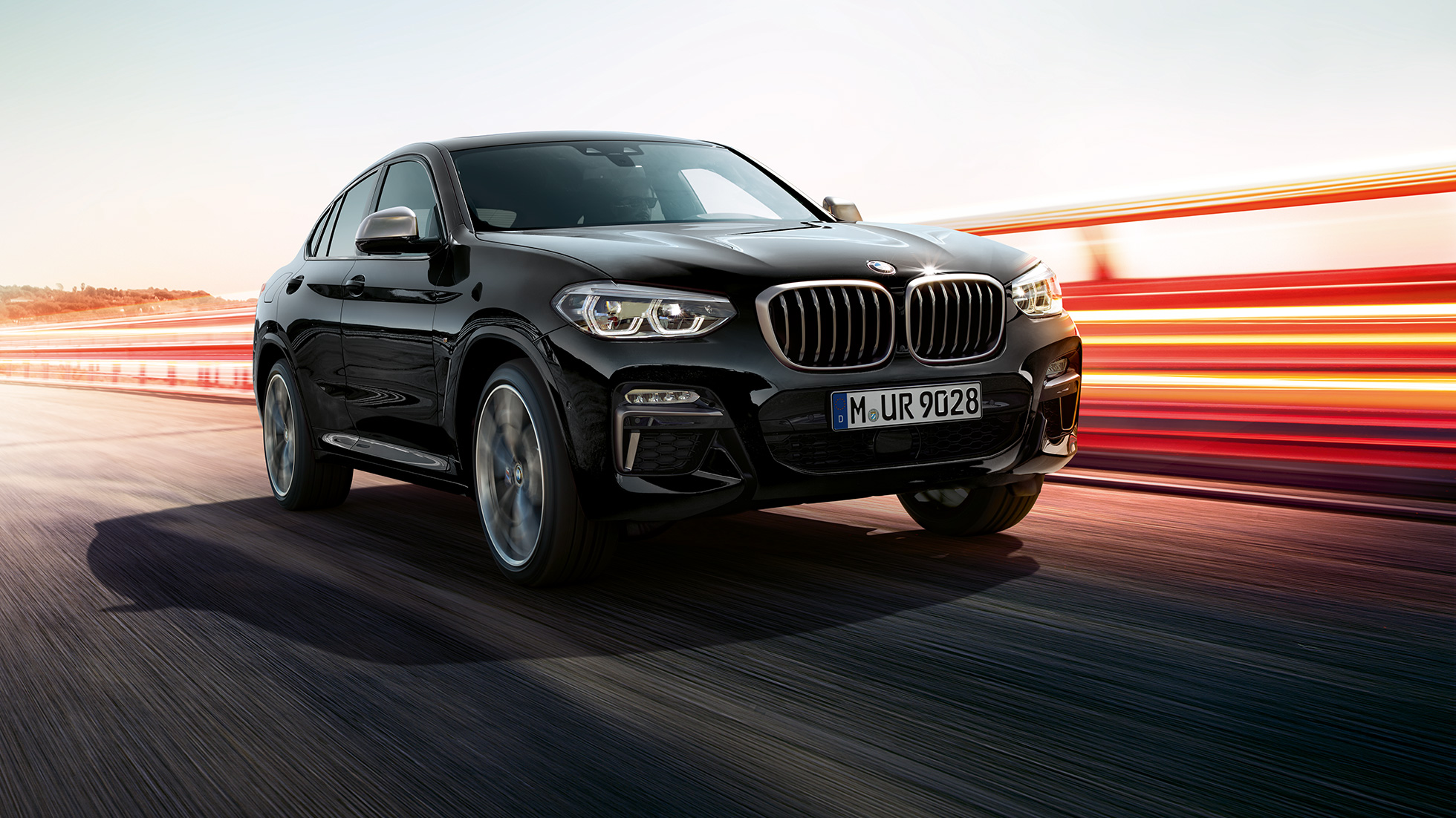 BMW X4 M40i SUV, three-quarter front view F98. BMW X4 M40i SUV in Black Sapphire metallic, exterior, three-quarter front view, left side with light strips F98.