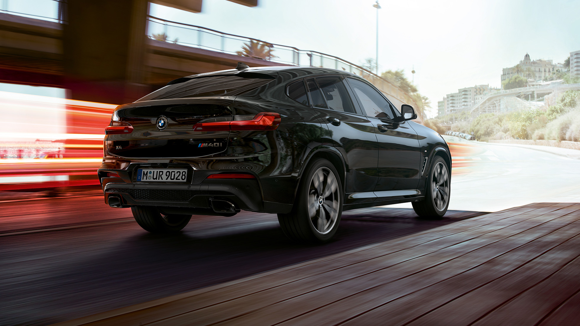 BMW X4 M40i SUV, three-quarter rear view F98. BMW X4 M40i SUV in Black Sapphire metallic, exterior, three-quarter rear view, right side with light strips F98.