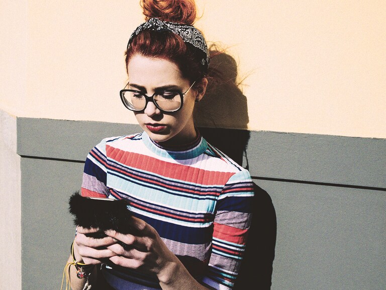 Internet of things: ragazzina con i capelli rossi guarda il cellulare